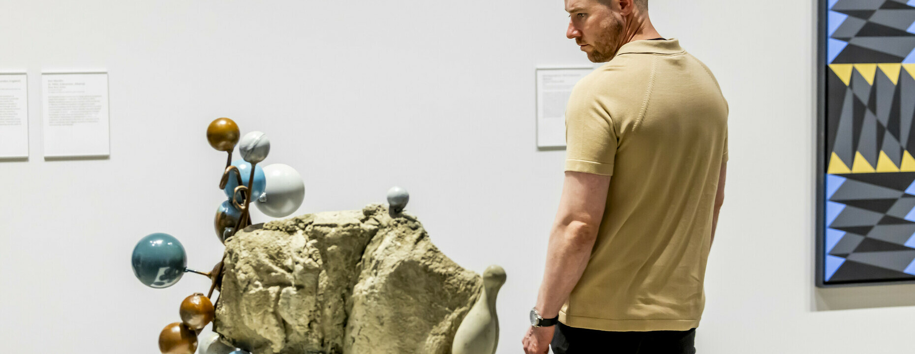 A man looks at a sculpture with circular bulbs protruding from it.