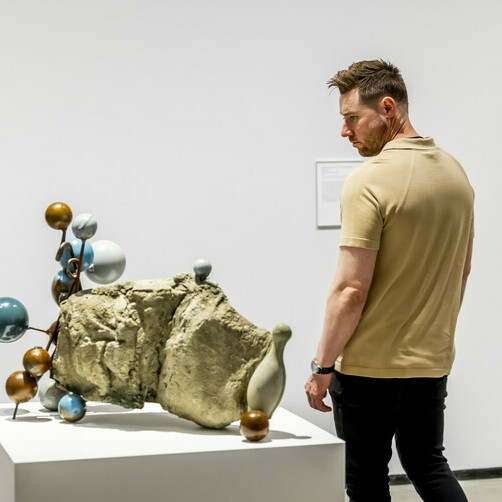 A man looks at a sculpture with circular bulbs protruding from it.