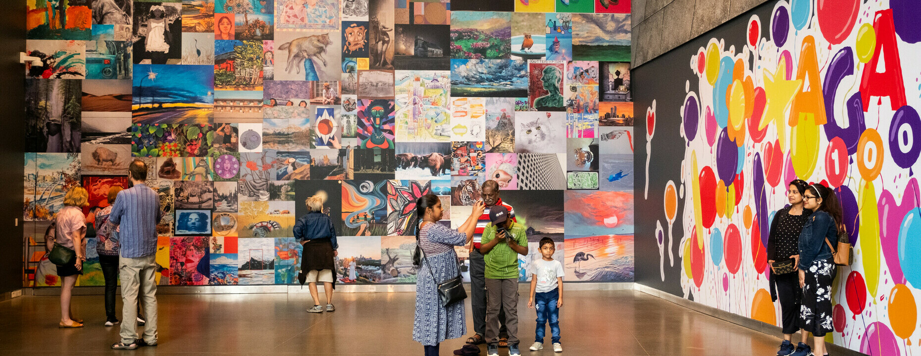 A group of people explore a wall filled with multicoloured art created by the community.