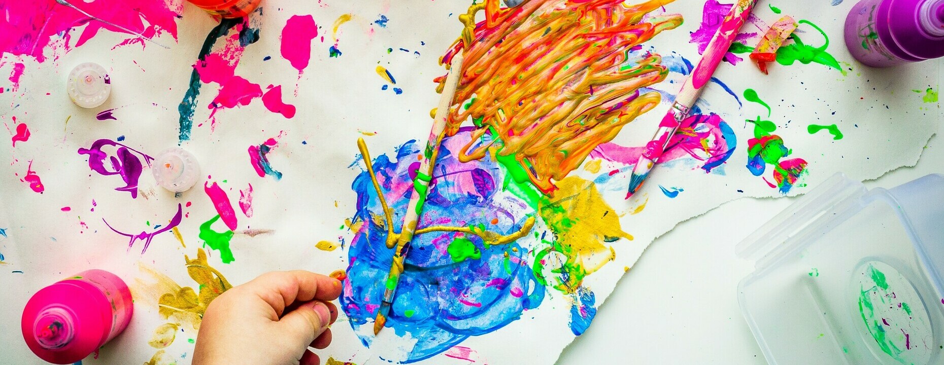 Splashes of pink, orange and green paint on a paper.